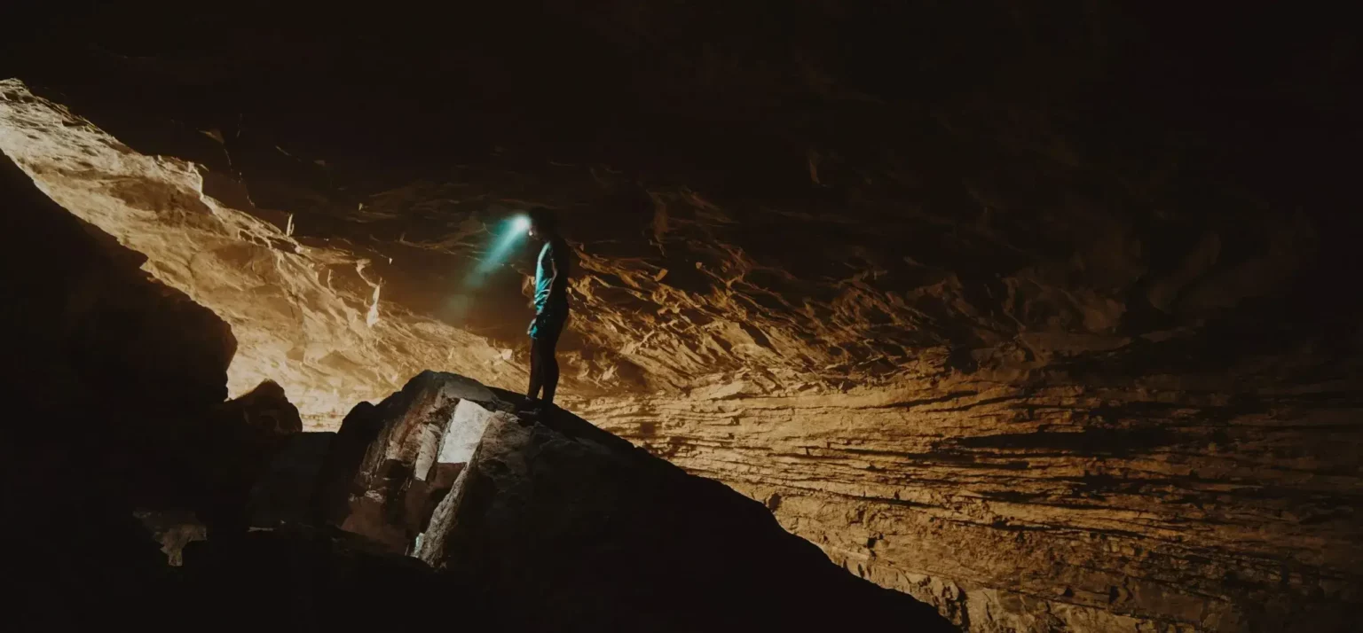 A person with a headlamp in a cave