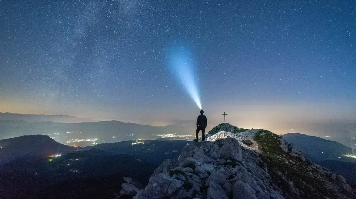 Une personne avec une lampe frontale en haut d'une montagne la nuit