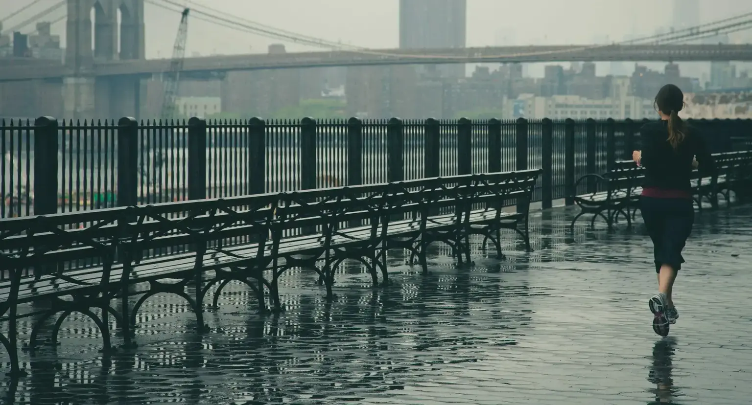 Un jogger che corre sotto la pioggia in città