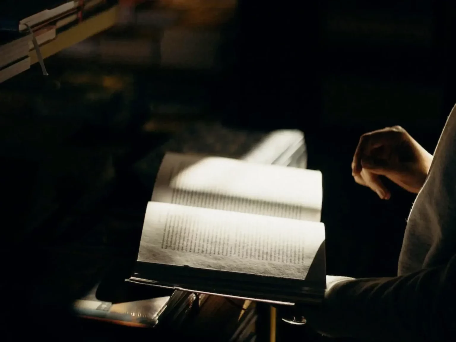 Giovane donna che legge un libro al buio utilizzando una lampada da lettura